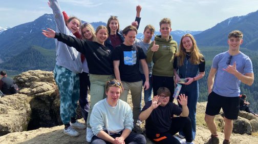 a group of young people pose on a mountain top